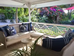 exclusive caribbean style sitting open air living area surrounded by blooming bushes