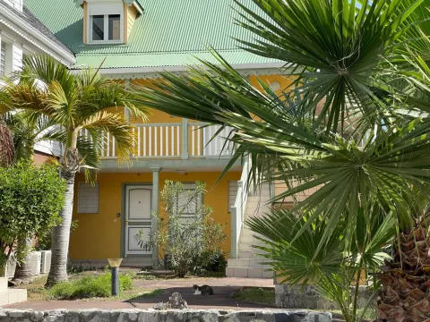 french style two floor yellow house with outside stairs and porch