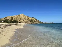 Hill In Backdrop Along Shoreline With Clear Water As Photography Location