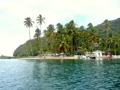 Palm Island In Front Of Massive Mountain With Fishing Boats