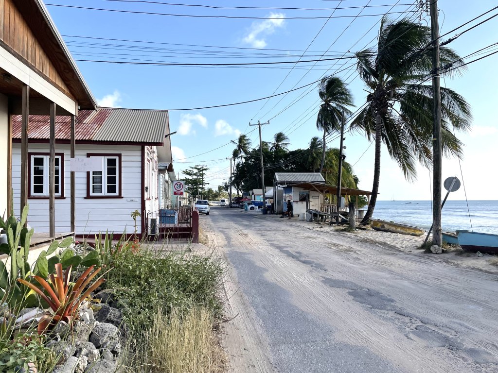 Fishing village with small wood houses and coconut trees lining along the straight street on the beach